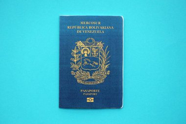 Venezuelan passport book on light blue paper background close up. Travel document on blue surface