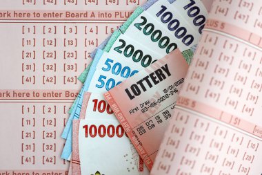 KYIV, UKRAINE - JANUARY 27, 2024 Red lottery ticket lies on pink gambling sheets with indonesian rupiah money bills. Lottery playing concept or gambling addiction in indonesia
