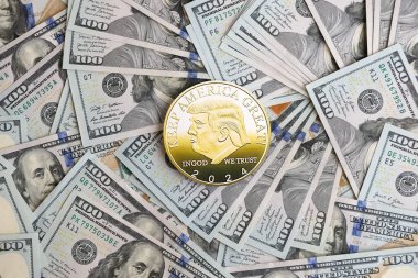 KYIV, UKRAINE - 13 Aralık 2025 Büyük miktardaki 100 dolarlık banknotlar üzerinde Trump altın madeni para