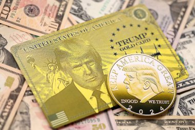 KYIV, UKRAINE - 13 Aralık 2025 Trump altın kartı ve hatıra parası büyük miktarda Amerikan doları banknotları yakın plan