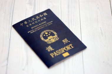 Hong Kong Özel İdari Bölgesi HKSAR pasaportu ahşap masa arkasında, yakın planda. Hong Kong mavi pasaport defteri.