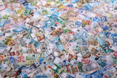 Dünyanın çeşitli para birimlerinden farklı renkte banknotlar. Masada yığınla para var. Yakın plan.