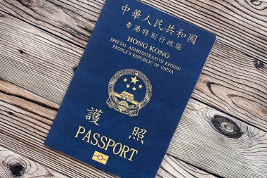 Hong Kong Özel İdari Bölgesi HKSAR pasaportu ahşap masa arkasında, yakın planda. Hong Kong mavi pasaport defteri.