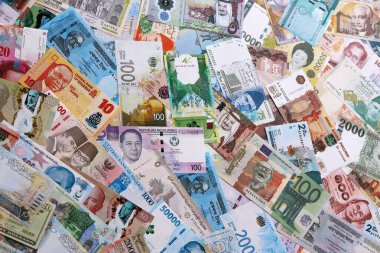 Dünyanın çeşitli para birimlerinden farklı renkte banknotlar. Masada yığınla para var. Yakın plan.