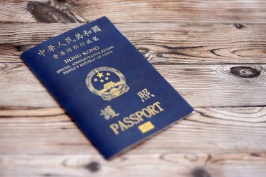 Hong Kong Özel İdari Bölgesi HKSAR pasaportu ahşap masa arkasında, yakın planda. Hong Kong mavi pasaport defteri.