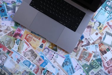 Modern dizüstü bilgisayarın üzerinde farklı para birimlerinden gelen banknotlar var.