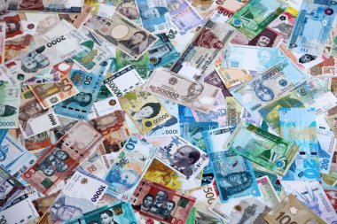 Dünyanın çeşitli para birimlerinden farklı renkte banknotlar. Masada yığınla para var. Yakın plan.