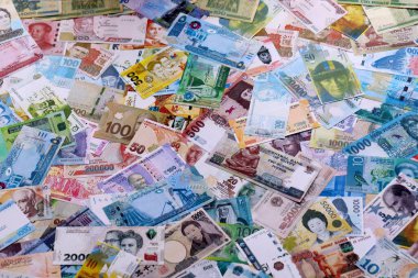 Dünyanın çeşitli para birimlerinden farklı renkte banknotlar. Masada yığınla para var. Yakın plan.