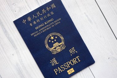 Hong Kong Özel İdari Bölgesi HKSAR pasaportu ahşap masa arkasında, yakın planda. Hong Kong mavi pasaport defteri.