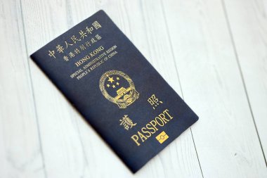 Hong Kong Özel İdari Bölgesi HKSAR pasaportu ahşap masa arkasında, yakın planda. Hong Kong mavi pasaport defteri.
