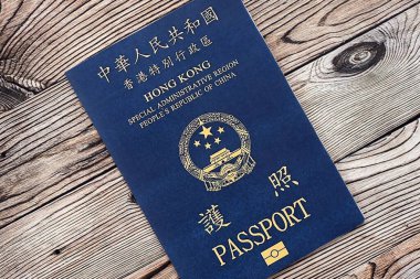 Hong Kong Özel İdari Bölgesi HKSAR pasaportu ahşap masa arkasında, yakın planda. Hong Kong mavi pasaport defteri.