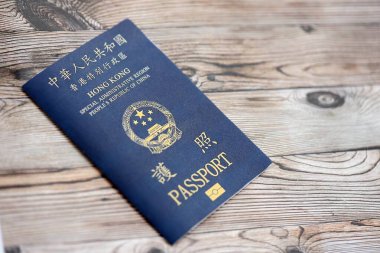 Hong Kong Özel İdari Bölgesi HKSAR pasaportu ahşap masa arkasında, yakın planda. Hong Kong mavi pasaport defteri.