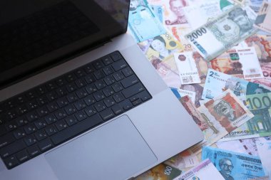 Modern dizüstü bilgisayarın üzerinde farklı para birimlerinden gelen banknotlar var.