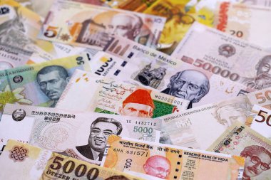 Çeşitli para birimleri para banknotları sarı ve turuncu renklerde. Farklı ülkelerden gelen birçok nakit para yığını yakın mesafede. Dünya ekonomisi ve döviz kuru kavramı