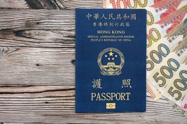 Hong Kong Special Administrative Region HKSAR Passport lies on flag with money bills banknotes close up. Hong Kong blue new passport book in details