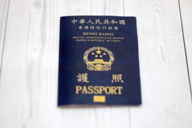 Hong Kong Özel İdari Bölgesi HKSAR pasaportu ahşap masa arkasında, yakın planda. Hong Kong mavi pasaport defteri.