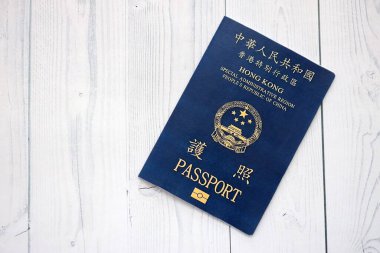 Hong Kong Özel İdari Bölgesi HKSAR pasaportu ahşap masa arkasında, yakın planda. Hong Kong mavi pasaport defteri.