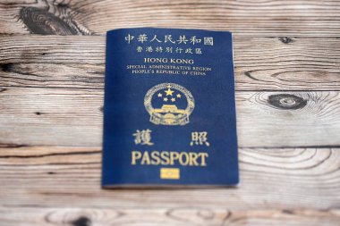 Hong Kong Özel İdari Bölgesi HKSAR pasaportu ahşap masa arkasında, yakın planda. Hong Kong mavi pasaport defteri.
