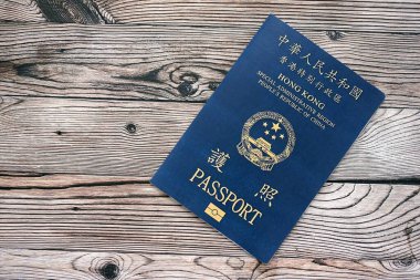 Hong Kong Özel İdari Bölgesi HKSAR pasaportu ahşap masa arkasında, yakın planda. Hong Kong mavi pasaport defteri.