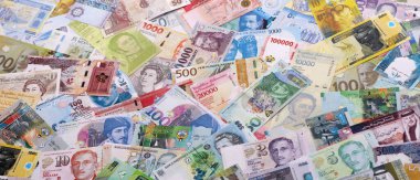 Dünyanın çeşitli para birimlerinden farklı renkte banknotlar. Masada yığınla para var. Yakın plan.