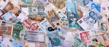 Dünyanın çeşitli para birimlerinden farklı renkte banknotlar. Masada yığınla para var. Yakın plan.