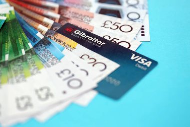 KYIV, UKRAINE - 28 Ocak 2026 Cebelitarık Uluslararası Bankası kartı ve Gibraltarian Pound para faturaları yakın planda. Cebelitarık Uluslararası Bankası Cebelitarık 'taki en popüler bankadır.