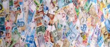 Dünyanın çeşitli para birimlerinden farklı renkte banknotlar. Masada yığınla para var. Yakın plan.