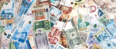 Dünyanın çeşitli para birimlerinden farklı renkte banknotlar. Masada yığınla para var. Yakın plan.