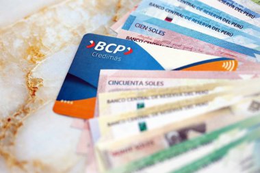 KYIV, UKRAINE - 28 Ocak 2026 BCP Banco de Credito del Peru kartı ve Peru sol para faturaları yakın planda. BCP Banco de Credito del Peru, Peru 'nun en popüler bankasıdır.