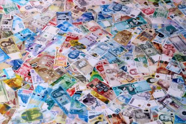 Dünyanın çeşitli para birimlerinden farklı renkte banknotlar. Masada yığınla para var. Yakın plan.