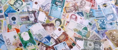 Dünyanın çeşitli para birimlerinden farklı renkte banknotlar. Masada yığınla para var. Yakın plan.