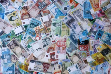 Dünyanın çeşitli para birimlerinden farklı renkte banknotlar. Masada yığınla para var. Yakın plan.