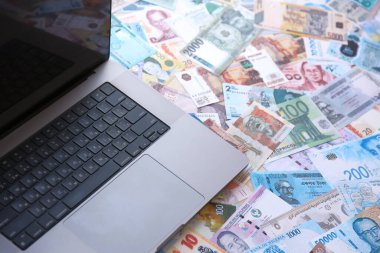 Modern dizüstü bilgisayarın üzerinde farklı para birimlerinden gelen banknotlar var.