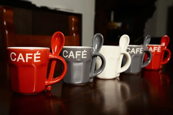 Цветные чашки кофе на деревянном столе — стоковое фото