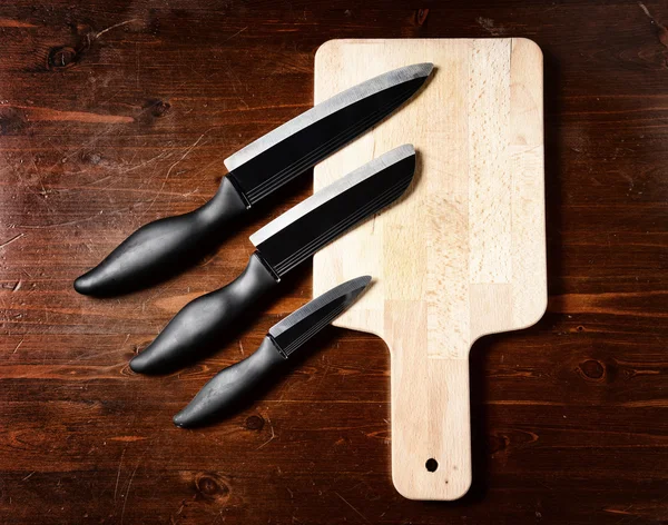 sharp knives and chopping board on dark wooden table