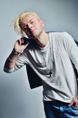 Yakışıklı genç moda erkek model ile ceket omzunun üzerinden poz. Beyaz arka plan üzerinde izole tam vücut uzunluğu portre.