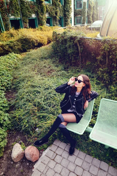 Modèle de mode en lunettes de soleil et veste en cuir noir posant en plein air — Photo