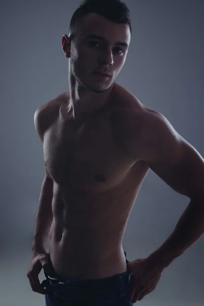 Young handsome guy posing in a studio with a beautiful body — Stock Photo, Image