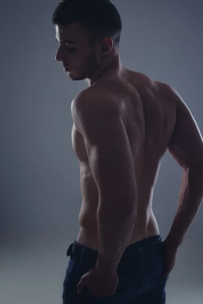 Young handsome guy posing in a studio with a beautiful body — Stock Photo, Image