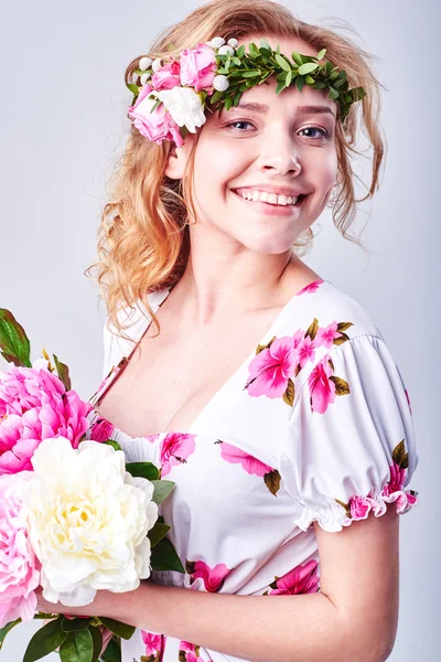 Menina beleza leva flores bonitas em suas mãos. A soprar flor. Penteado com flores. Retrato menina fantasia em cores pastel. Retrato de fadas de verão. Cabelo longo com permanente . — Fotografia de Stock