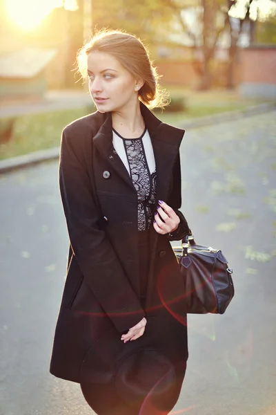 A menina bonita jovem anda na rua com um casaco e chapéu w — Fotografia de Stock
