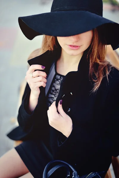 La giovane bella ragazza cammina per strada in cappotto e cappello con una borsa — Foto Stock