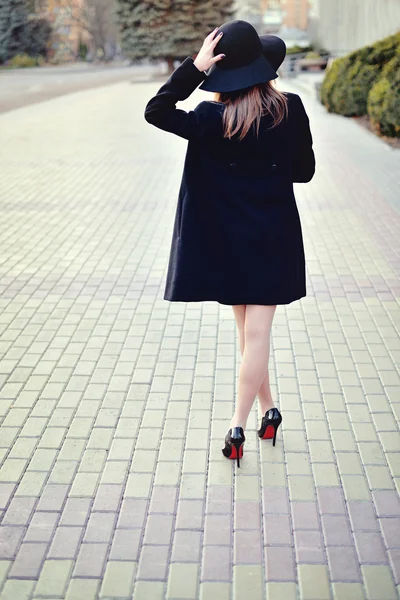 La jeune belle fille marche dans la rue avec un manteau et un chapeau w — Photo