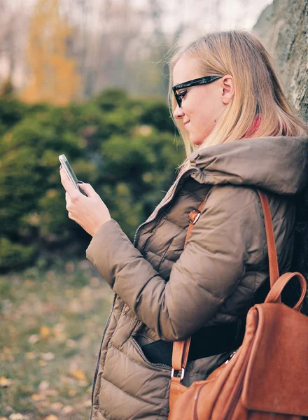 Ritratto di una studentessa. Gli occhiali con il telefono, a riposo in un parco . — Foto Stock