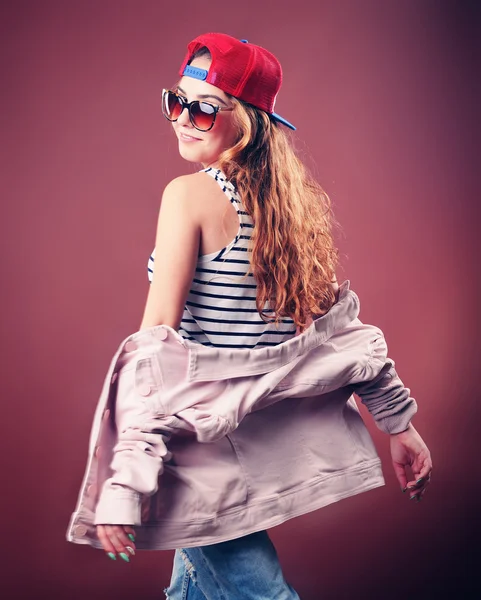 Sexy donna hip-hop in berretto con lunghi capelli rossi. Ritratto di moda della ragazza moderna in cap — Foto Stock