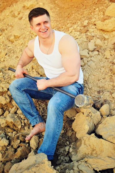 Young angry businessman crashing bricks with hammer — Stock Photo, Image