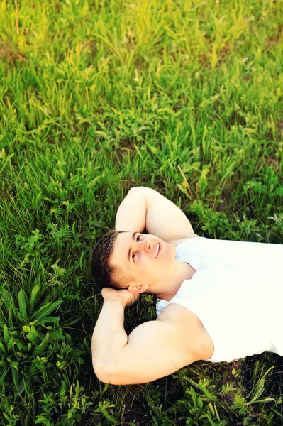 Relaxado jovem deitado na grama em um prado — Fotografia de Stock