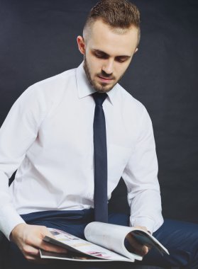 Başarılı bir iş adamı. Kollarını çapraz tutarken ve gri arka plana karşı dururken kameraya bakan ve gülümseyen formalgiyimli kendine güvenen genç adamın portresi