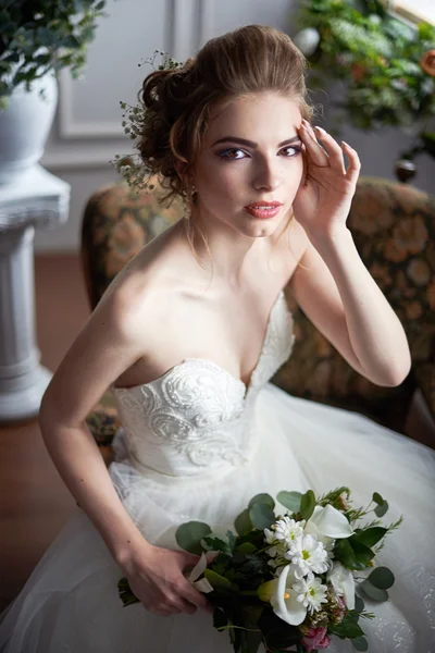 Eine Braut in einem wunderschönen Kleid mit einem Strauß Blumen und Grün. Hochzeit. Brautstrauß. Brautmorgen. Kunsthochzeit. glückliche Braut wartet Bräutigam. — Stockfoto