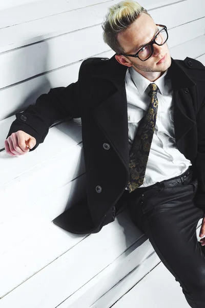 Fashion portrait of young man in black shirt poses over wall with contrast shadows — Stock Photo, Image